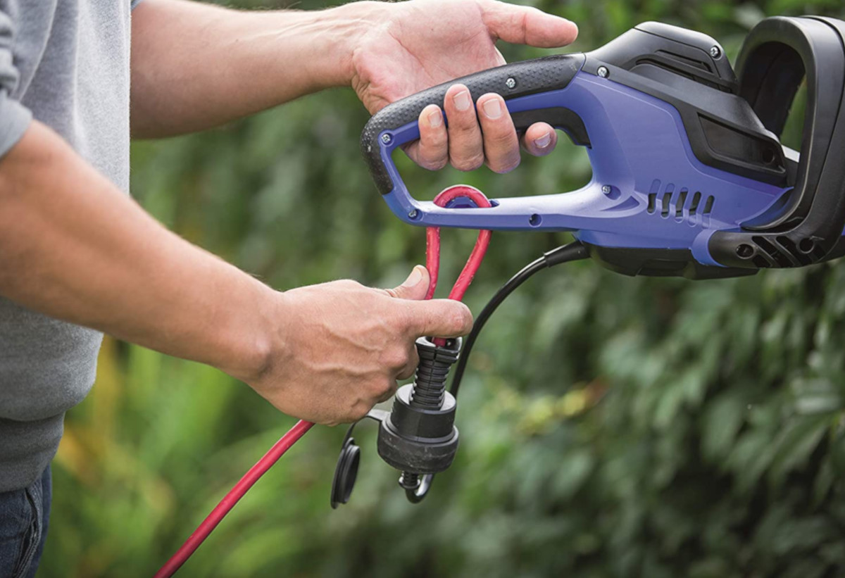 Απεικονίζονται χέρια ενος ανθρώπου να κρατούν το ηλεκτρικό μπορντουροψάλιδο.